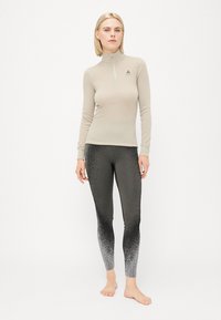 Light beige zip-up long-sleeve top paired with black leggings featuring a gradient pattern transitioning from dark to light gray.