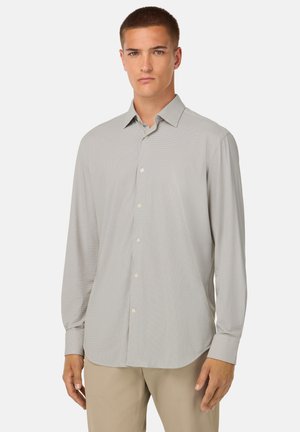 Camisa de manga larga gris claro con un sutil patrón de diamantes, cuello de botón y frente abotonado. Hecha de una tela suave con un corte relajado.