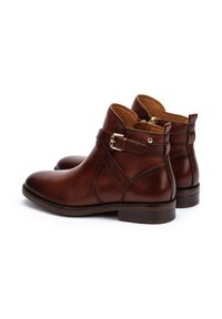 Brown leather ankle boots with a round toe, side buckle detail, and a low heel. Smooth texture with subtle stitched accents.