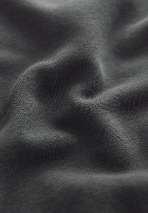 Makro záber na tmavosivé tkanivo s jemnou pletenou textúrou a jemnými záhybmi vytvárajúcimi subtílne tiene.