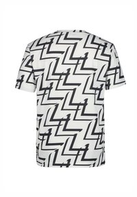 Camiseta de manga corta en una tela ligera que presenta un patrón de zigzag negro sobre un fondo blanco. Cuello redondo con un corte regular.