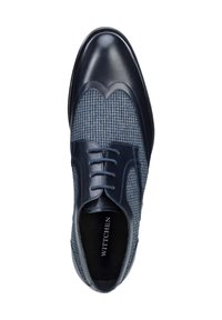 Zapato de vestir para hombre que presenta una combinación de cuero azul oscuro y tela texturizada en un patrón a cuadros, con cordones y un diseño de punta redondeada.