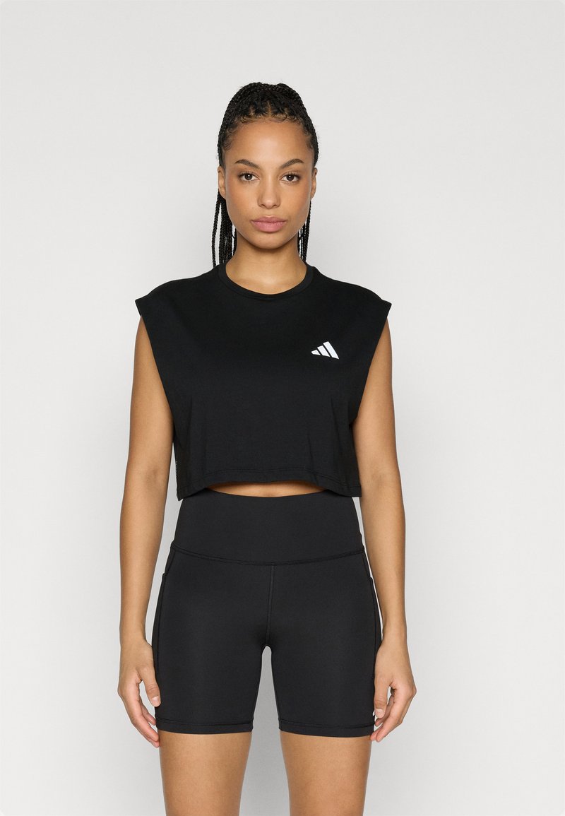 Μαύρο cropped αμάνικο τοπ από απαλό ύφασμα με στρογγυλή λαιμόκοψη και λευκό λογότυπο Adidas. Συνδυασμένο με ψηλόμεσο μαύρο σορτς.