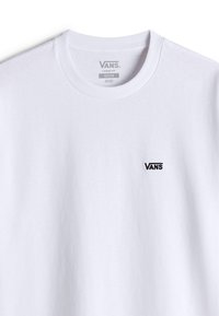 T-shirt en coton blanc à coupe loose. Il présente un col rond et un petit logo "VANS" noir brodé sur la poitrine.
