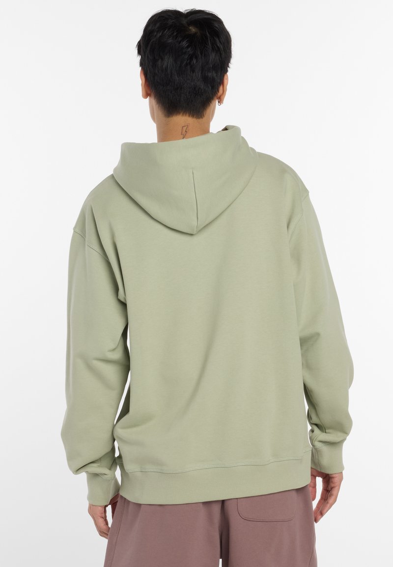 Sweat à capuche vert clair avec une capuche spacieuse, des manches longues et des poignets côtelés. Il présente une coupe décontractée et une texture de tissu douce.