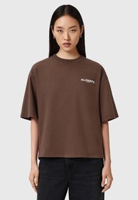 Camiseta de algodón marrón con mangas cortas, que presenta un logo blanco "ALLSAINTS" en el pecho. Corte cuadrado y textura suave.