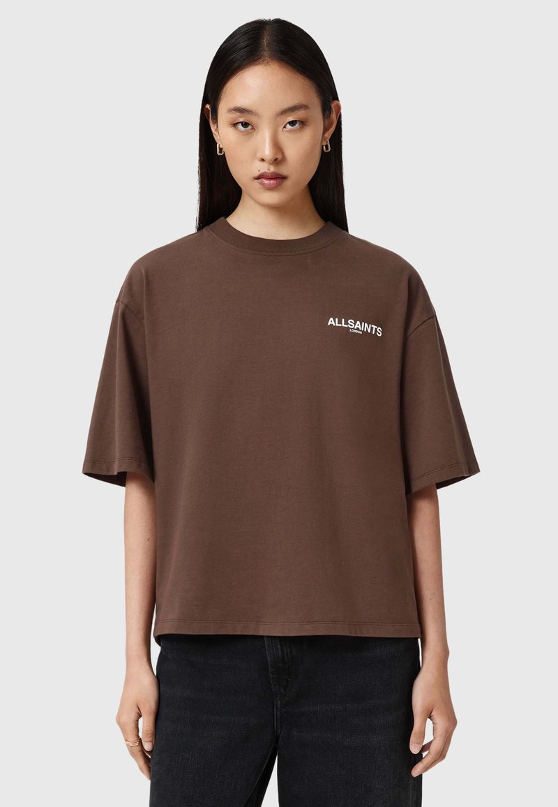 Camiseta de algodón marrón con mangas cortas, que presenta un logo blanco "ALLSAINTS" en el pecho. Corte cuadrado y textura suave.