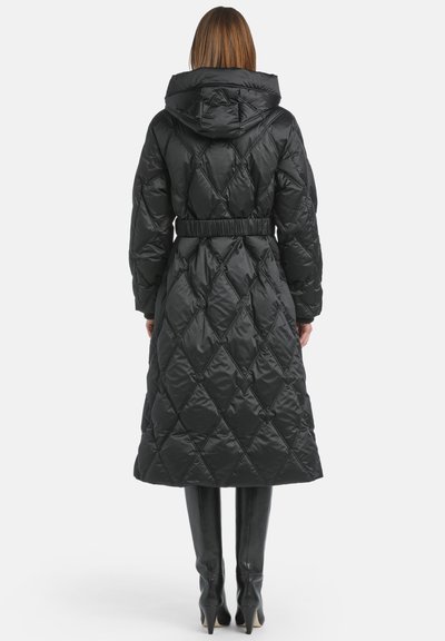 Pardoseală lungă neagră tip puffer, cu un model cu diamant, talie elastică și glugă. Materialul pare lucios și neted, asociat cu cizme negre până la genunchi.