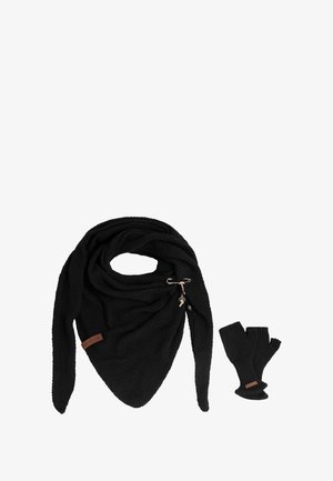 Zwarte gebreide driehoekige sjaal met metalen speld en trekkoord, gecombineerd met zwarte vingerloze handschoenen, op een witte achtergrond.
