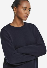 Dunkelblauer gestrickter Pullover mit runder Ausschnitt und lockerer Passform. Verfügt über gerippte Bündchen und Saum, weiche Textur und ein minimalistisches Design.