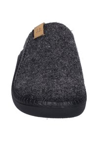 Pantufla de fieltro gris oscuro con un diseño curvado, suela de goma negra y una pequeña etiqueta de cuero marrón claro con "J.S." cosida.