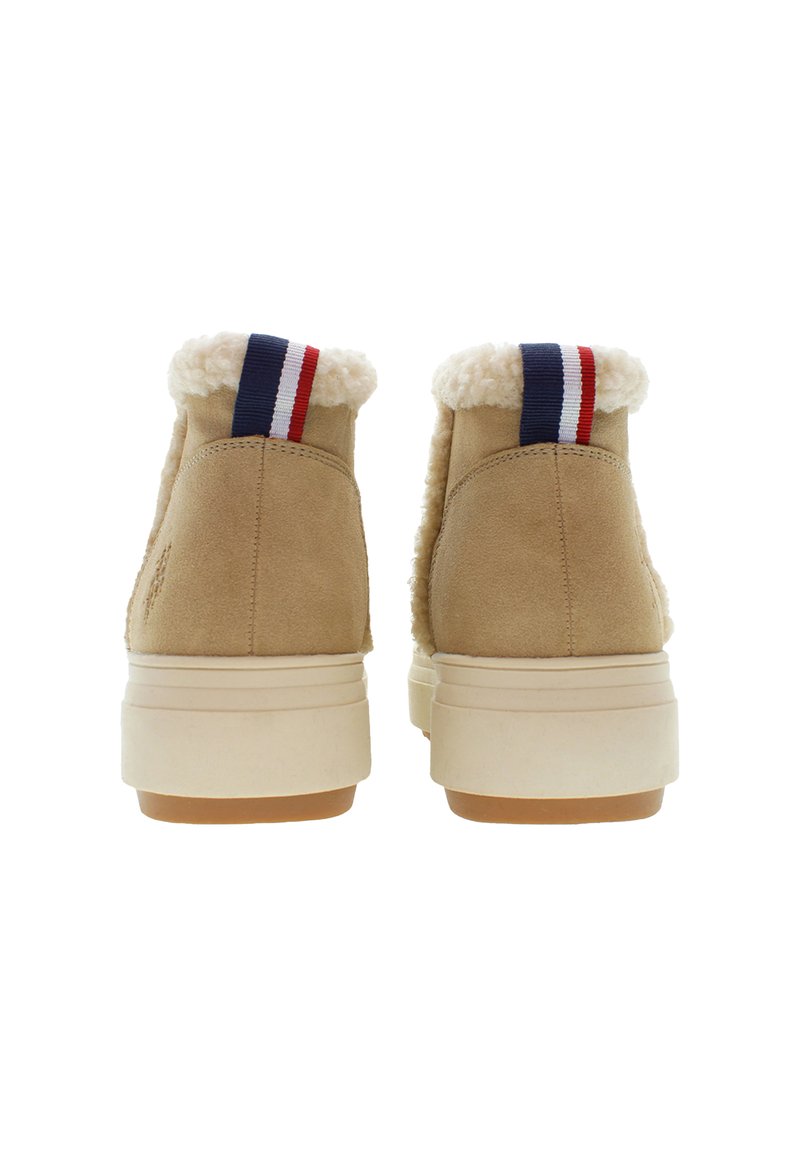 Para beżowych zimowych butów z zamszu, z białym futerkiem wewnątrz i czerwono-biało-niebieskimi uchwytami, widziana z tyłu na białym tle.