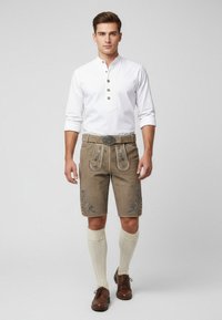 Men's traditional outfit featuring a white long-sleeve shirt with a placket and beige lederhosen with floral embroidery and a decorative belt.