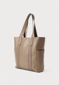 Beige læder tote taske med dobbelte skulderremme, der har et præget "Calvin Klein" logo på forsiden og en sidelomme. Glat tekstur.