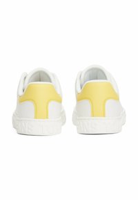 Sneakers bianchi con accenti gialli sul tallone, suole texturizzate e logo del brand impresso sul lato; presentano una parte superiore in materiale sintetico liscio e un collare imbottito.