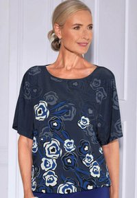 Marineblauwe bloemenblouse met korte mouwen, gemaakt van lichtgewicht stof. Heeft abstracte witte en blauwe bloempatronen en een ronde halslijn.