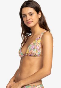 Trikotna bikini zgornji del v pastelnih cvetličnih motivih, ki vključujejo odtenke roza, rumene in zelene. Ima tanke naramnice in globok V-izrez.