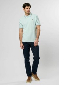 Ljus mynta grön polo skjorta med korta ärmar, prydd med en liten emblem. Kombinerad med mörka jeans och bruna mocka sneakers.