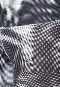 Legginsy w czarno-białe wzory z kropeczkami, z logo Adidas. Wykonane z elastycznego, lekkiego materiału o gładkiej fakturze.