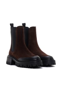 Botines de ante marrón con paneles laterales elásticos, una puntera de goma negra y una suela resistente, que presentan un tacón grueso y un acabado texturizado.