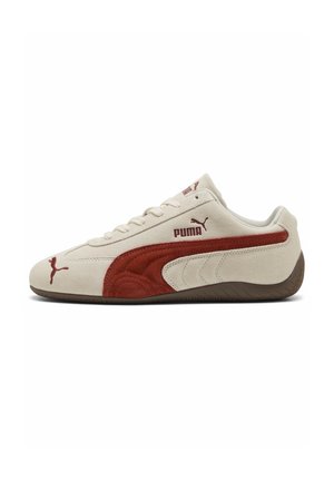 Lavprofileret beige ruskind Puma-sneaker med rød ruskindsstribe, brun sål og Puma-logo på siden og tungen.