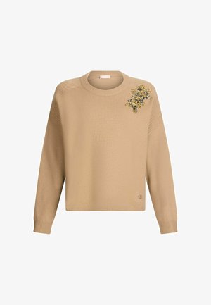 Beige strikket sweater med lange ærmer, rund halsudskæring, ribbet manchetter og et udsmykket blomstermotiv på venstre skulder.