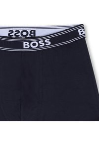 Μπλε σκούρα ανδρικά εσώρουχα τύπου μποξεράκια με λευκή ελαστική μέση με λογότυπο, που διαθέτει αντιθετικές ρίγες και λεία υφή.