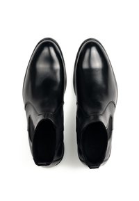 Zwarte leren enkellaarzen met een gladde afwerking, elastische zijpanelen, afgeronde neus en zonder zichtbare hardware of patronen.