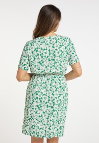 Kortärmad klänning med figursydd midja, prydd med ett grönt och vitt blommönster på ett lättviktsmaterial. Mjuk textur, knälång.