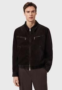 Μαύρο μπουφάν από κορδούρα με γιακά, δύο τσέπες στο στήθος με φερμουάρ, πλαϊνές τσέπες και ορατό φερμουάρ μπροστά. Λείος υφής.