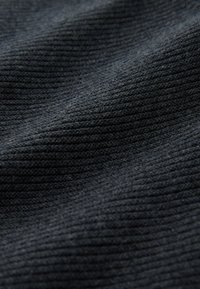 Tissu en maille gris foncé avec une texture côtelée, présentant des lignes et des variations subtiles. Le matériau semble doux et légèrement élastique.