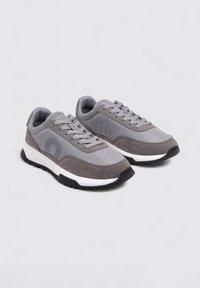 Zapatillas grises con una combinación de texturas lisas y de gamuza, que presentan una entresuela blanca y una suela de goma negra. Diseño con cordones que incluye marca.