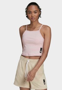 Top corto de canalé color rosa claro con tirantes finos y escote cuadrado, combinado con pantalones cortos beiges con cordones y acentos de logo.