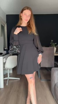 Črna obleka z prosojnimi, napihnjenimi dolgimi rokavi, A-linijskim krilom in prilegajočim pasom. V kombinaciji s črno umetniško torbico, ki ima bele risbe.