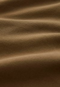 Hnedká textúrovaná tkanina s viditeľnými tkanými vzormi, so zamatovými, hladkými záhybmi a matným povrchom. Ideálna na rôzne textilné aplikácie.