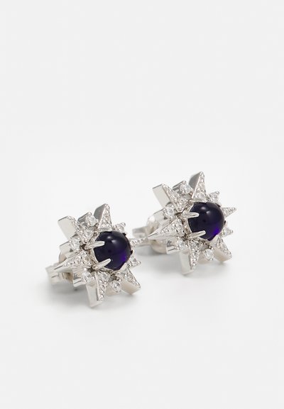 Silver star-shaped earrings featuring a central purple stone and surrounding clear crystals, creating a contrast in colors and textures.