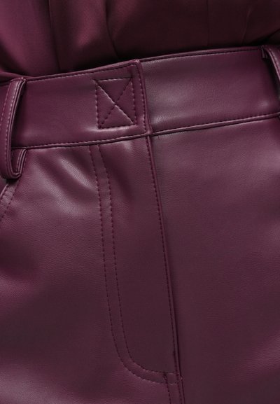 Vijolične punkarske hlače iz umetnega usnja z všitim pasom, sprednjimi žepi ter gladko teksturo in subtilnim sijajem. Prilegajoč kroj s čistimi linijami.