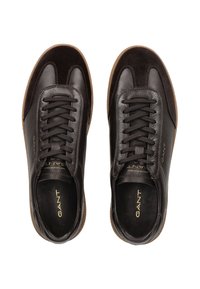 Zapatillas de cuero marrón oscuro con acentos de ante, punta redonda, suela de goma texturizada y cordones planos, con un logo dorado en el costado.