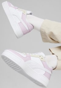 Sneakers bianchi con accenti rosa e gialli, caratterizzati da una texture in pelle liscia, suola in gomma piatta e dettagli cuciti in evidenza.