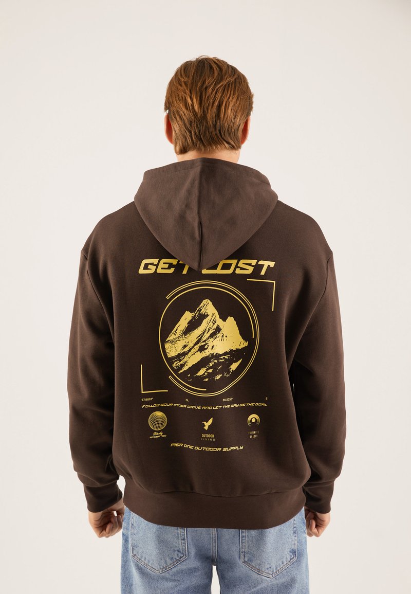 Felpa marrone con una grande grafica di montagna gialla e il testo "GET LOST" sul retro. Presenta una tasca frontale e un cappuccio con cordino.