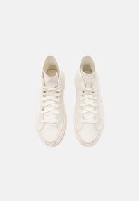 Wysokie trampki w off-white z kanwy z okrągłymi noskami, płaskimi sznurowadłami i teksturowanymi gumowymi podeszwami. Minimalistyczny design z subtelnymi detalami w szwie.