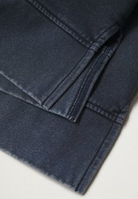 Pantaloni in denim blu scuro con una texture liscia, caratterizzati da cuciture piatte e un orlo piegato. Il tessuto presenta un leggero sbiadimento in alcune aree.