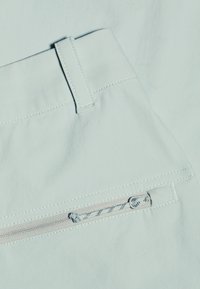 Lichtblauwe stoffen shorts met een tailleband, voorzien van witte stiknaden en een ritsvak aan de zijkant voor veilige opslag.