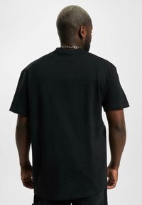 Black cotton t-shirt with short sleeves, a relaxed fit, and a crew neckline. Visible stitching and smooth texture at the back.