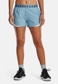 Ljusblå träningstights med en svart "Under Armour" midja, vita sidopaneler, tillverkade av slät syntetisk material.