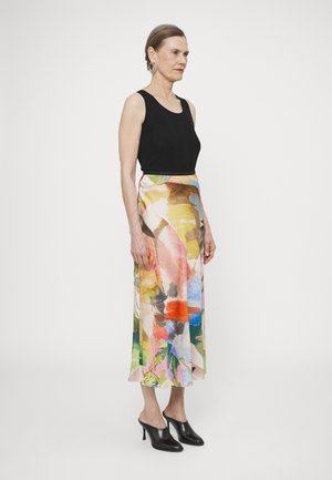 Schwarzes ärmelloses Top kombiniert mit einem mehrfarbigen, seidenen bodenlangen Rock mit abstrakten Mustern. Schwarze hohe Mules vervollständigen den Look.