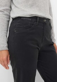 Zwarte katoenen jeans met een gladde textuur, vijf-pocket ontwerp en contrasterende stiksels. Voorzien van een metalen knoop en ritssluiting.