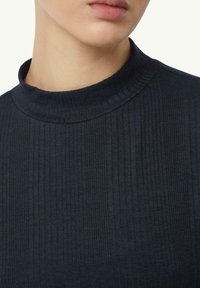 Riblany, granatowy golf z wysokim kołnierzem i fakturowanym materiałem, zbliżenie na szyję i górną część klatki piersiowej.