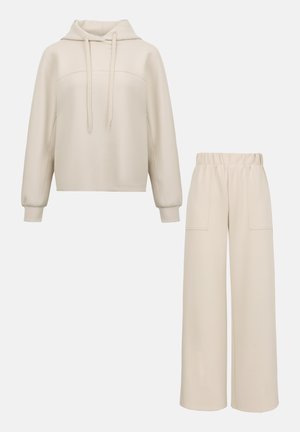 Sweat à capuche beige avec cordons et pantalon large assorti à taille élastique et grandes poches avant.