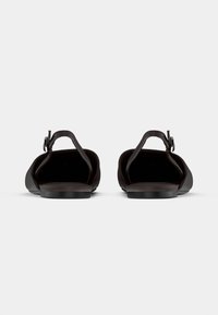 Černé sandály s širokým příčným prostorem na prsty, kotníkovým páskem a plochou podrážkou. Vyrobené z hladké kůže s minimalistickým designem a bez viditelných vzorů.